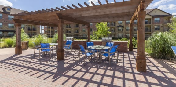 a patio with a table and chairs under a wooden pergola