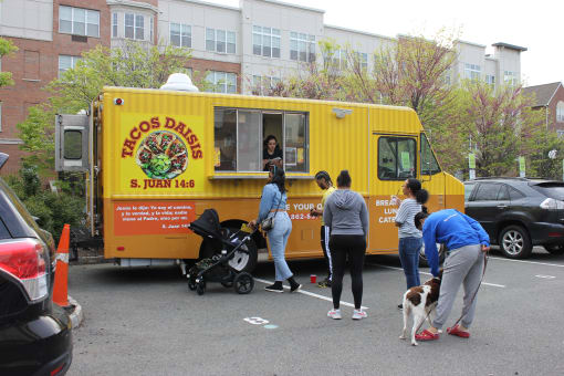 a group of people and a dog standing in front of a yellow food truck