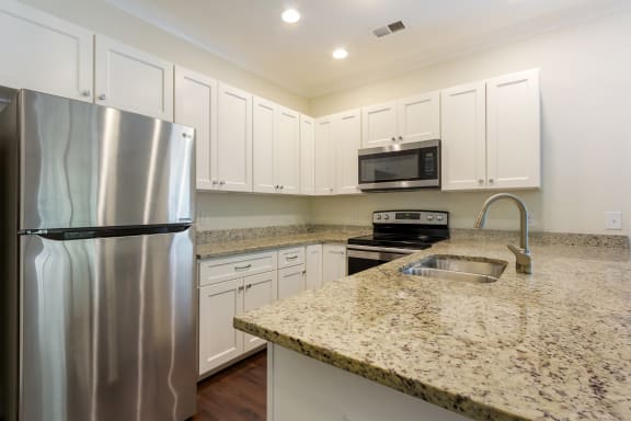 A kitchen with a granite countertop and stainless steel appliances at Waverly Place, North Charleston, SC, 29418