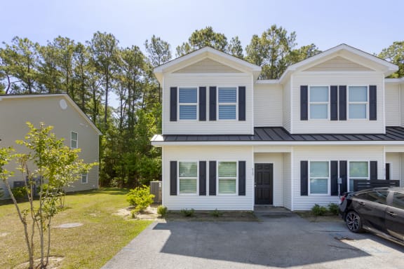 A white house with black shutters and a black car parked in front at Waverly Place, North Charleston, SC, 29418