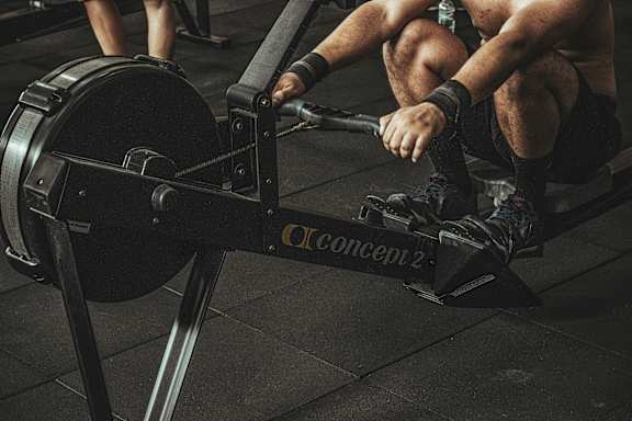 A man is sitting on a rowing machine in a gym.