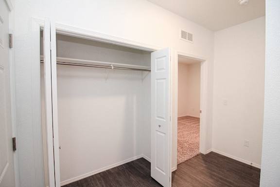 A white closet with a door open to a hallway.