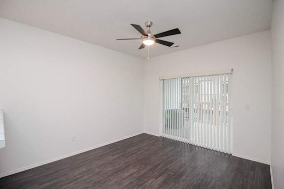 A room with a ceiling fan and a window with blinds.
