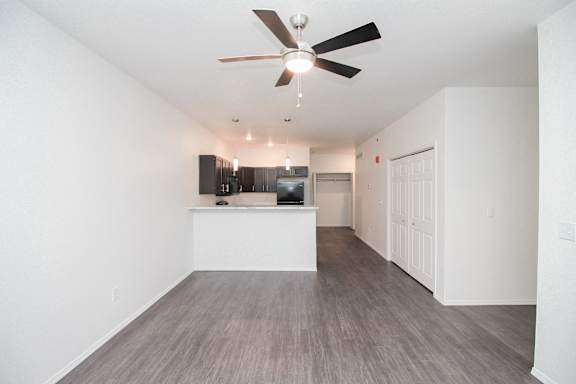 A room with a ceiling fan and a flat screen TV mounted on the wall.