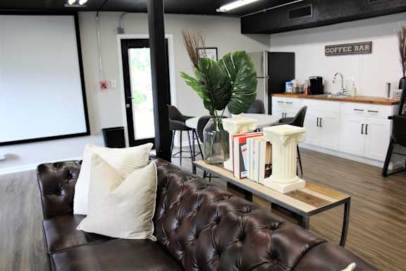 a living room with a brown leather couch and a coffee table at Capital Flats & Magnolia Square Apartments, Raleigh, NC