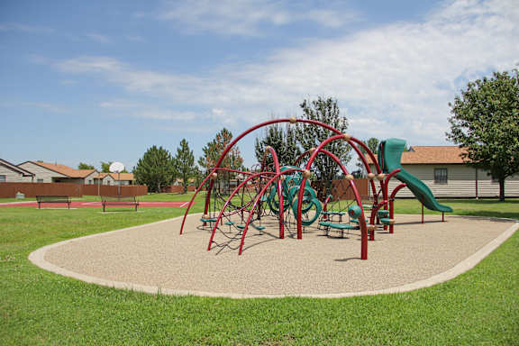 A playground with a red and green slide and a red and green climbing structure.