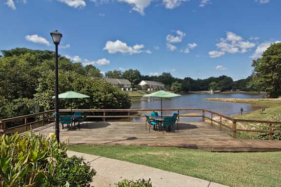 a deck overlooking a lake with tables and umbrellas at Lakecrest Apartments, PRG Real Estate Management, Greenville, South Carolina