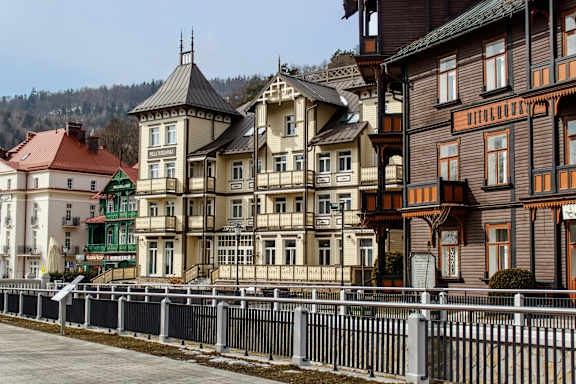 A row of colorful houses with a white fence in front.