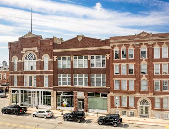 A large red brick building with a black car parked in front.