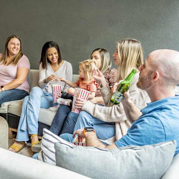 A group of people sitting in a living room eating popcorn and drinking beer at Gateway Gardens Apartments.