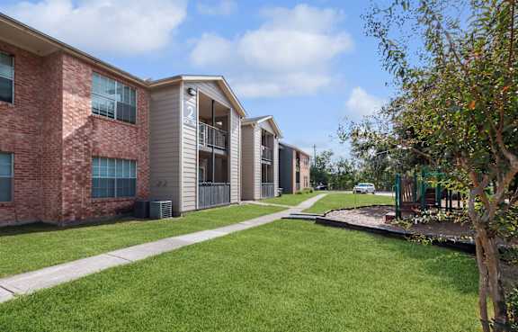 A row of apartment buildings with a green lawn in front.