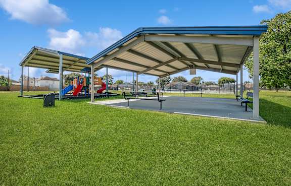 A playground with a blue canopy and a slide.
