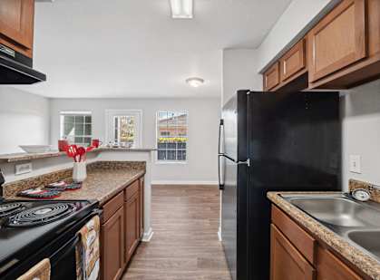 A black refrigerator sits in a kitchen with wooden cabinets.