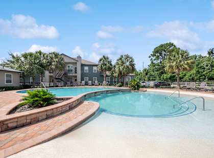 A swimming pool surrounded by palm trees and residential buildings.