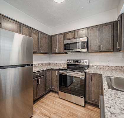 A kitchen with a stainless steel refrigerator, microwave, oven, and sink.
