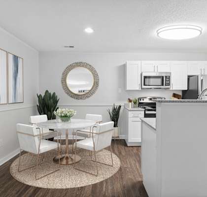 a dining area with a table and chairs and a kitchen in the background