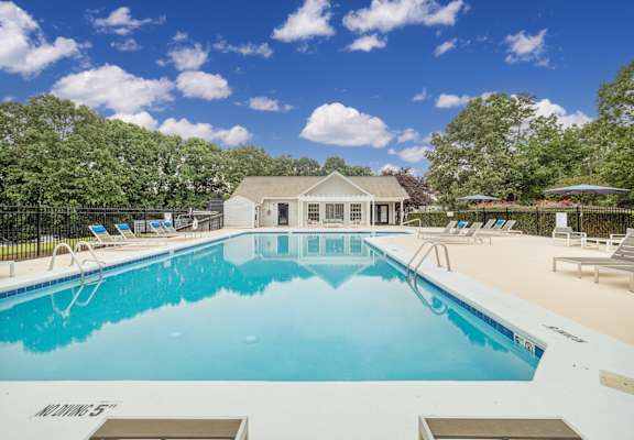 a pool with lounge chairs and a house in the background