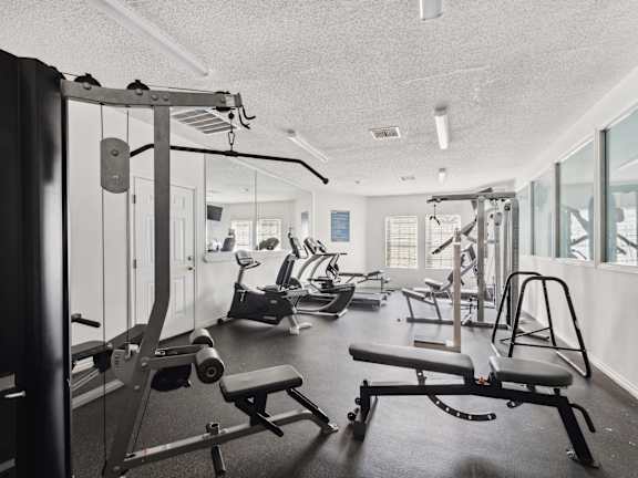 A gym with a variety of equipment including a squat rack, a leg press machine, and a bench press.