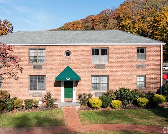 A red brick building with a green awning and a green door.