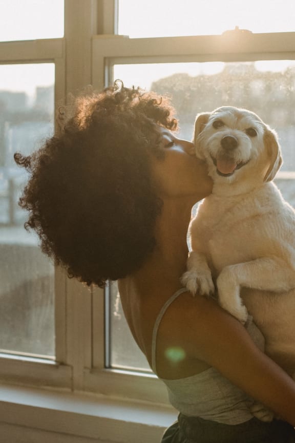 a woman holding a dog in front of a window