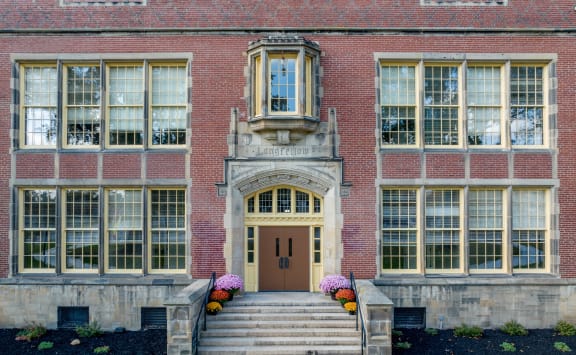 the front of a brick building with a brown door and stairs