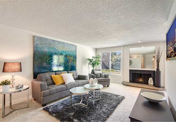 A living room with a grey couch, a coffee table, a fireplace, and a painting on the wall.