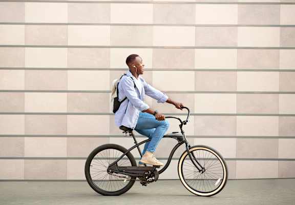 A man in a blue shirt and jeans is riding a bicycle.
