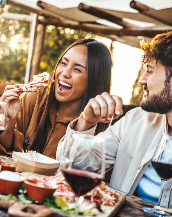 people sitting at a picnic table eating and drinking wine