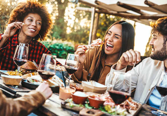 A group of people enjoying a meal and drinks at an outdoor dining area.