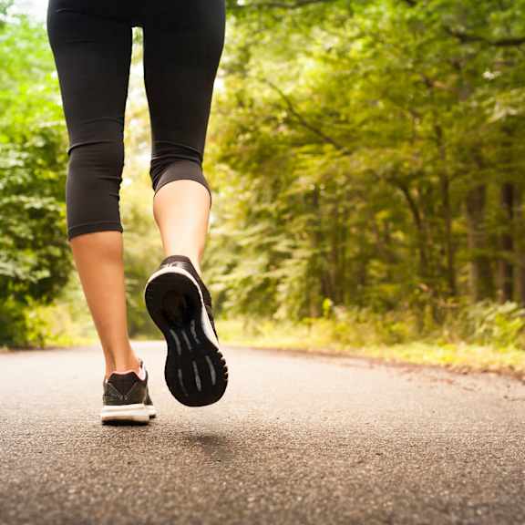A person is running on a road in the forest.