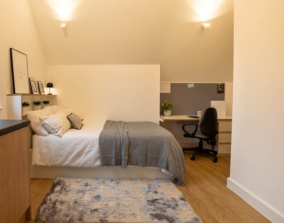 a bedroom with a bed and a desk with a chair