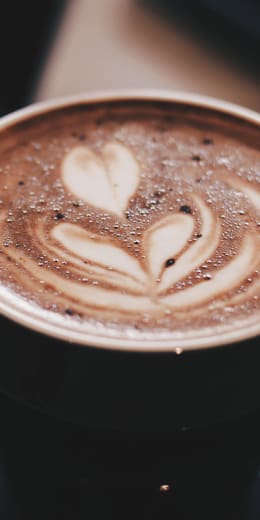 a cup of coffee with hearts on top