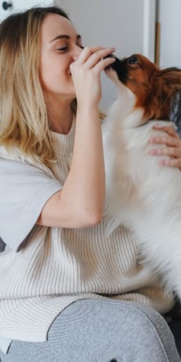 a woman sitting on a couch playing with her dog