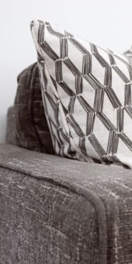 A grey couch with a geometric patterned pillow on it.
