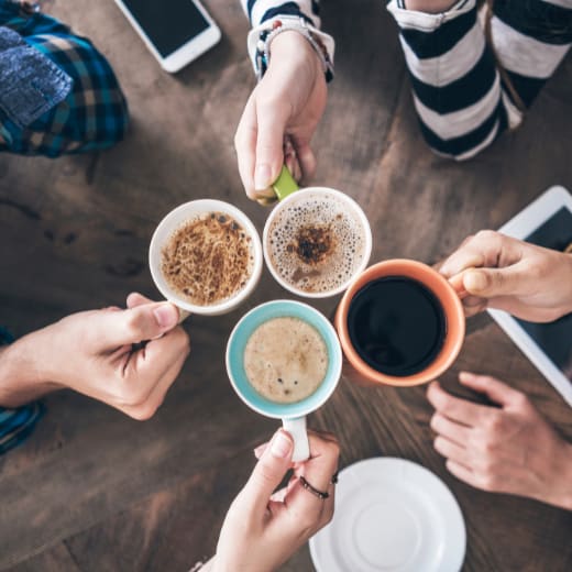 A group of people are gathered around a table, each holding a cup of coffee.