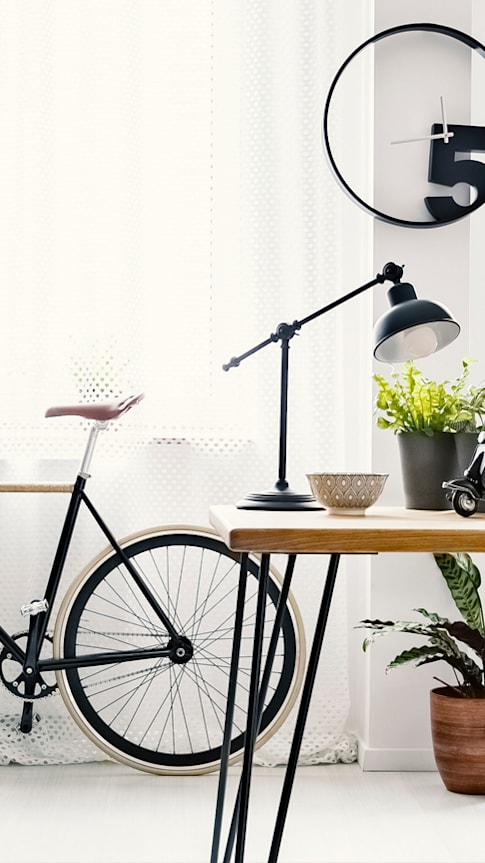 a bike parked next to a wooden table with a lamp and plants on it