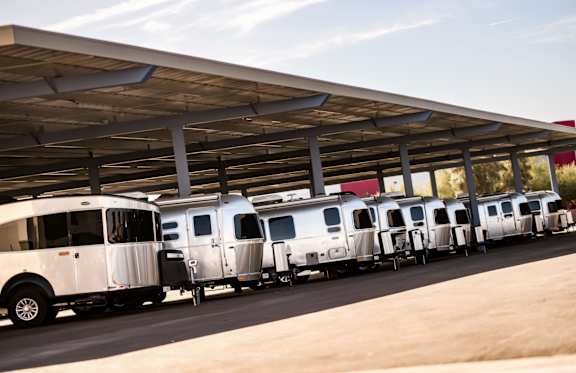 A row of airstreams parked under an outdoor covered space.