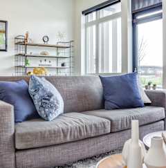 A grey couch with blue pillows sits in a living room.