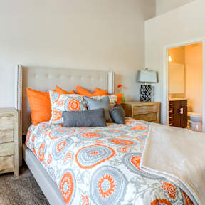 A bed with a white headboard and orange and blue bedspread.