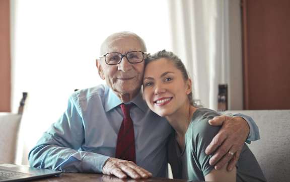 An older woman and a younger girl are sitting on a couch looking at a tablet.