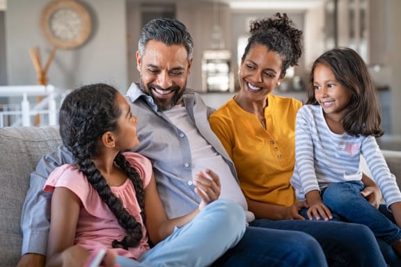 a family sitting on a couch in a living room looking at a tablet