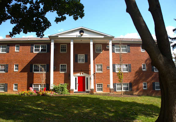 a large brick building with a red door and a tree