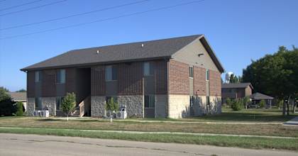 A large brick building with a grey roof and a small porch.