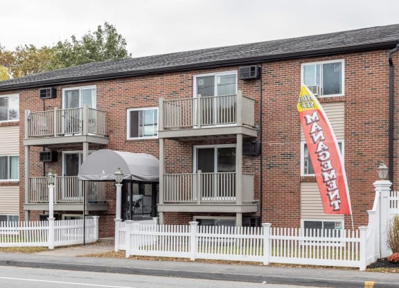 an apartment building with a red brick facade and a sign in front at Flats at Merrill Pond, Worcester