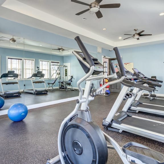 a gym with treadmills and weights and a tv