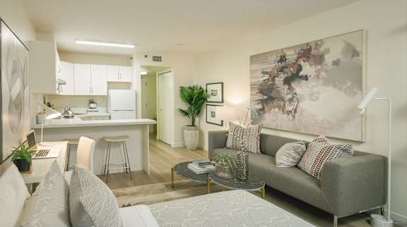 A modern living room with a grey couch and a large abstract painting on the wall.