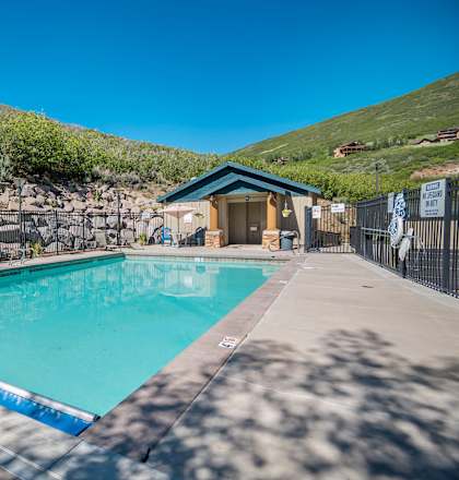 A pool with a blue border and a small building next to it.