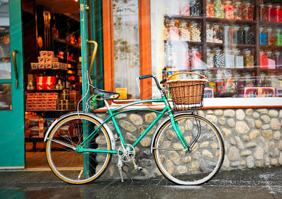 A bike with a basket is parked in front of a store.