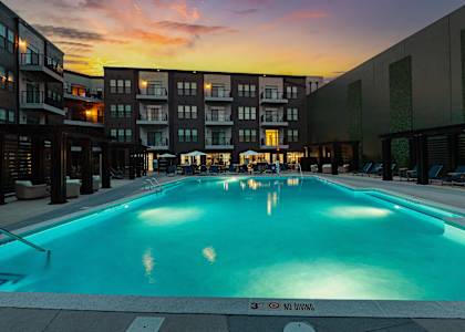 a swimming pool at dusk with an apartment building in the background
