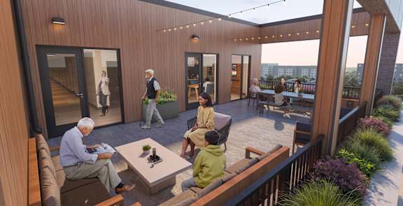 A group of people are sitting on a wooden deck with a table in the middle.